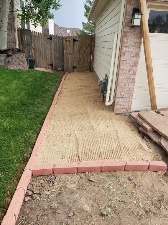 Paver edging and leveled sand base for a side-yard walkway