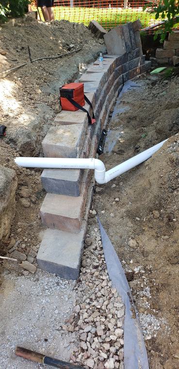 Block retaining wall with drainage pipe and gravel backfill